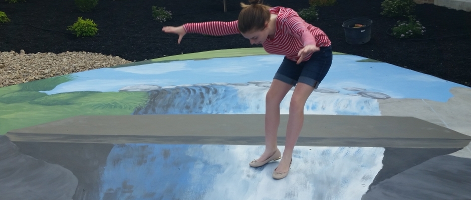 Young girl standing on waterfall perspective pavement art.