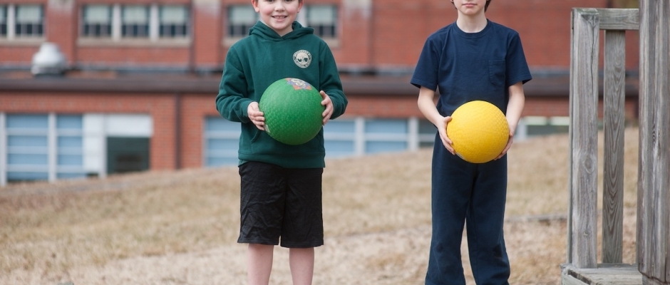 Two young boys holding playground balls.